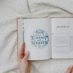 Open Bible with focus on Matthew passage and text Repent. Hands showing, resting on a quilt.
