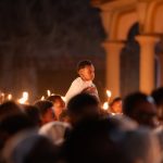 A boy on shoulders during a candlelit service at an Ethiopian church.